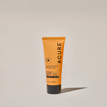 A yellow tube of ACURE Seriously Soothing SPF Day Cream with SPF 30 protection on a neutral bcakground